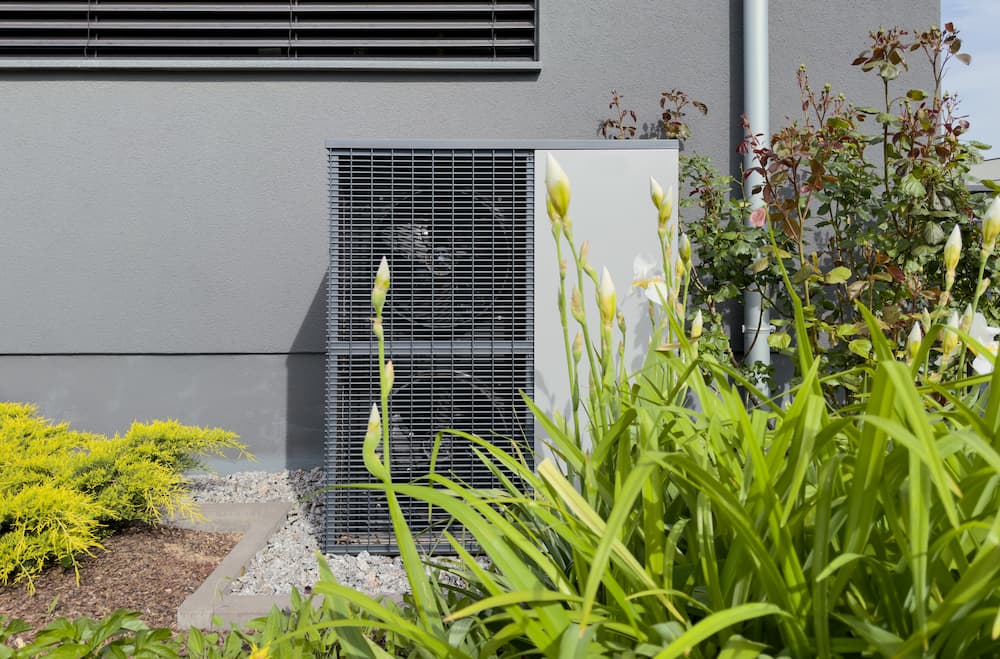 Close-up of an outdoor air-source heat pump compressor unit providing both heating and cooling for a contemporary home.