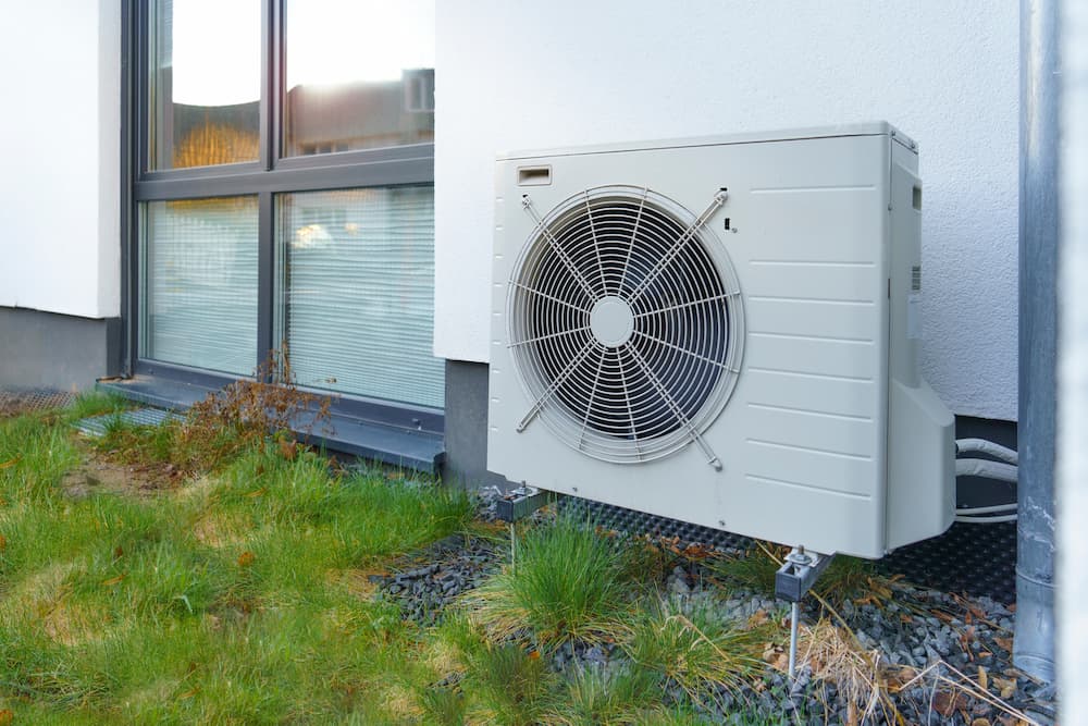 Outdoor heat pump unit installed beside a house.